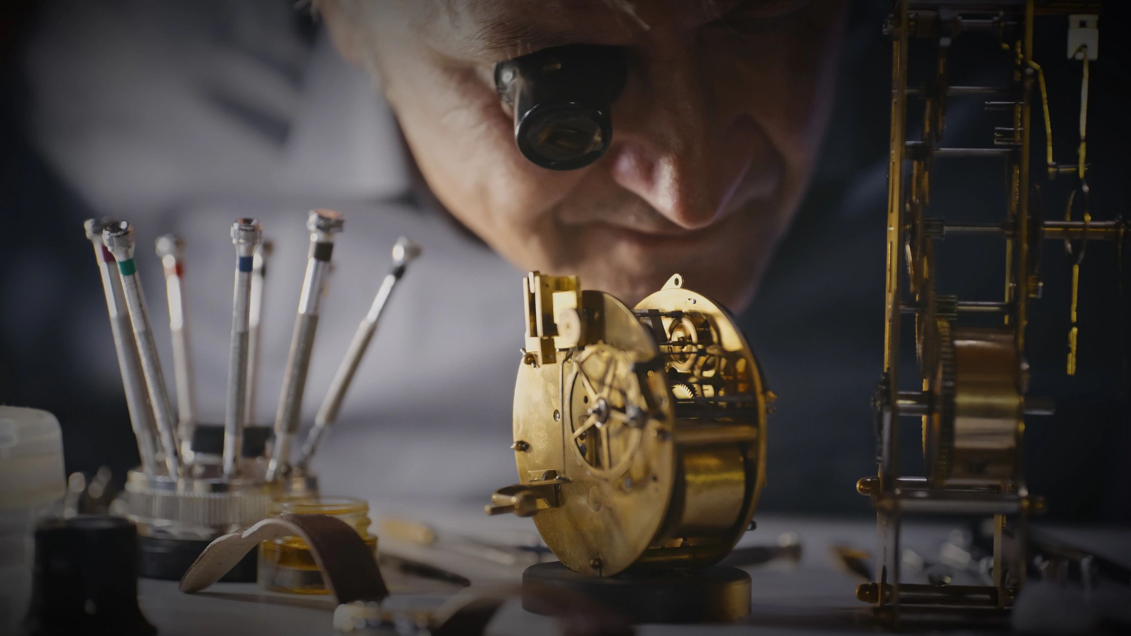 Clock repair specialist examining fine mechanical gears